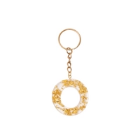 Keychain made of transparent resin decorated with shiny golden pieces - letter O