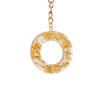 Keychain made of transparent resin decorated with shiny golden pieces - letter O