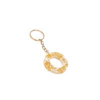 Keychain made of transparent resin decorated with shiny golden pieces - letter O