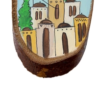 A handcrafted wooden decorative piece adorned with vibrant hand-painted illustrations depicting a city.