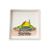 A square white dish decorated with an elaborate hand-painted drawing of the city of Jerusalem and the Dome of the Rock