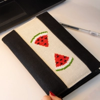 An elegant notebook with hand embroidery featuring a drawing of two watermelon pieces!