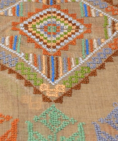 A beige shoulder scarf hand-embroidered with traditional patterns and vibrant colors