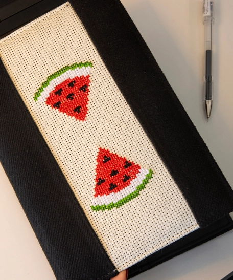 An elegant notebook with hand embroidery featuring a drawing of two watermelon pieces!