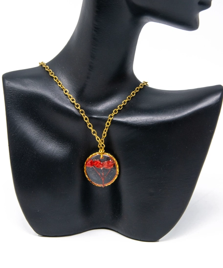 A gold necklace with a resin pendant containing a red flower inside.